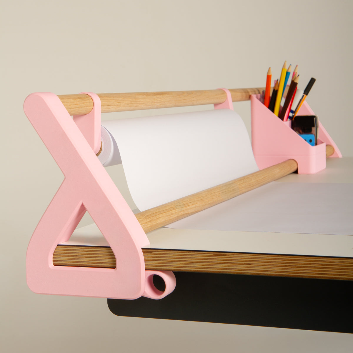 Das „Tiny Top Kids Set Schreibtischaufsatz Rosa“ von Smartfurniture GmbH ist ein rosa Schreibtischzubehör aus Holz, das speziell für den Kinder-Schreibtisch entwickelt wurde. Es verfügt über eine Halterung für eine Rolle weißes Papier sowie Fächer für Buntstifte und Kugelschreiber, die praktischerweise am Tischrand angebracht sind.